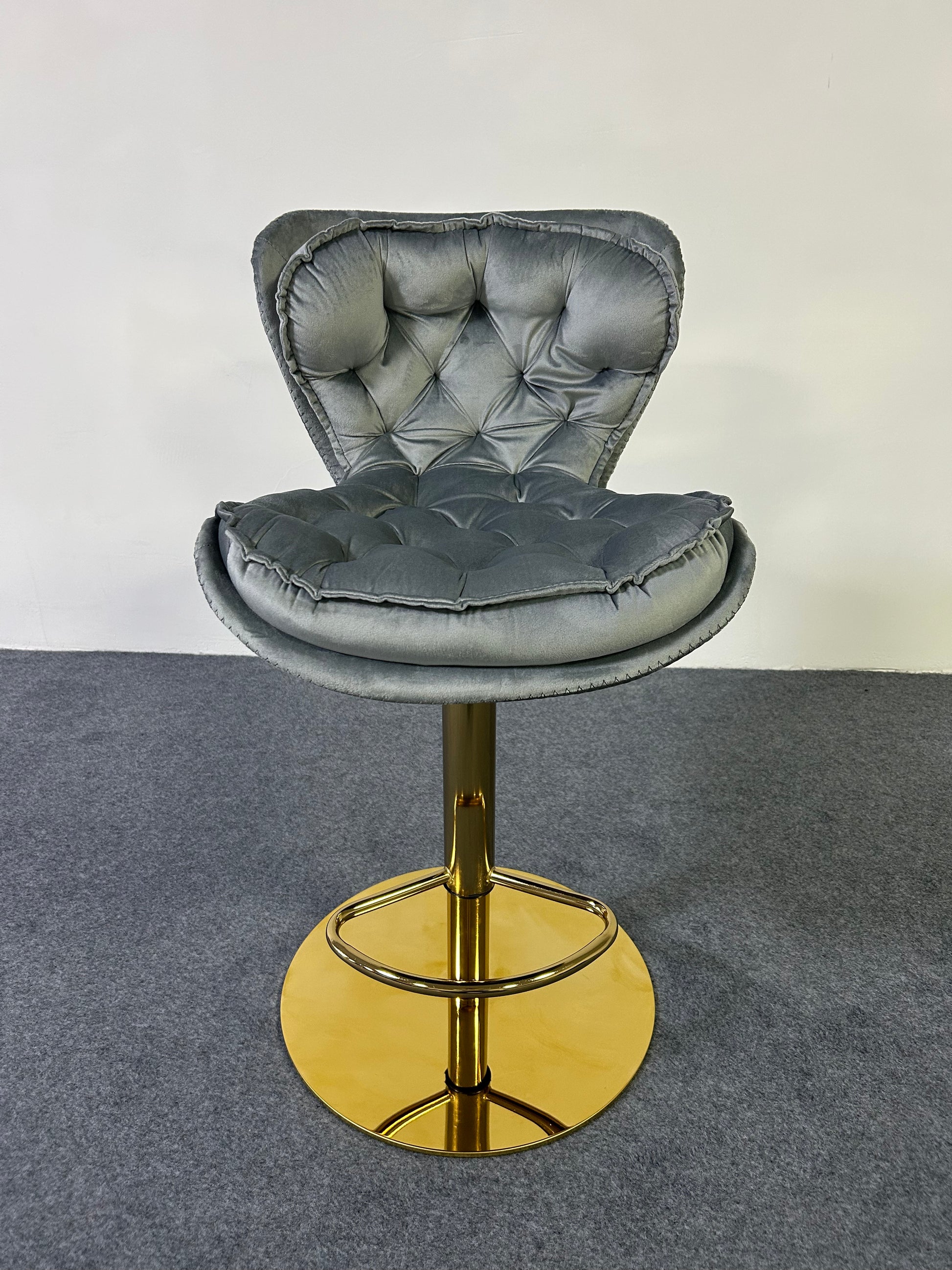 Luxury Golden Barstool with tufted gray upholstery and gold base on a gray carpet background.